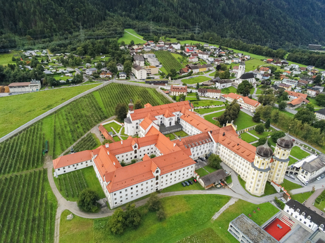 Aerial view of Stift Stams monastery with its distinctive red roofs courtyards and surrounding green fields in the alpine landscape of Stams Tirol Austria. Aerial view of Stift Stams monastery with its distinctive red roofs courtyards and surrounding green fields in the alpine landscape of Stams Tirol Austria.