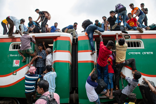 Dhaka Bangladesh 14 June 2018 View of people climbing and sitting on the roof of a crowded train at Airport Railway Station during the busy Eid festival commute. Dhaka Bangladesh 14 June 2018 View of people climbing and sitting on the roof of a crowded train at Airport Railway Station during the busy Eid festival commute.