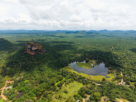 Aerial view of Sigiriya Lion Rock fortress surrounded by dense tropical jungle and a calm lake under a cloudy sky Sigiriya Central Province Sri Lanka. Aerial view of Sigiriya Lion Rock fortress surrounded by dense tropical jungle and a calm lake under a cloudy sky Sigiriya Central Province Sri Lanka.