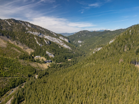 Aerial view of the lush Demanovska Dolina valley with dense coniferous forests and rocky mountain slopes under a clear blue sky in Demanovska Dolina Zilina Region Slovakia. Aerial view of the lush Demanovska Dolina valley with dense coniferous forests and rocky mountain slopes under a clear blue sky in Demanovska Dolina Zilina Region Slovakia.
