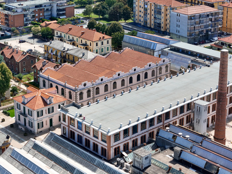 Aerial view of the historic Villaggio Leumann industrial complex with red tiled roofs and a tall brick chimney in Collegno Piemonte Italy. Aerial view of the historic Villaggio Leumann industrial complex with red tiled roofs and a tall brick chimney in Collegno Piemonte Italy.