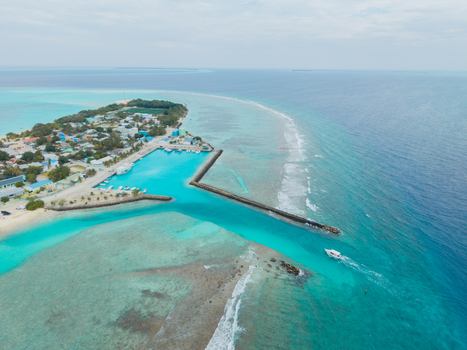Aerial view of the azure sea contrasting with the island s sandy beaches and the dark breakwater Vashafaru Island Thiladhummathi Atoll Maldives. Aerial view of the azure sea contrasting with the island s sandy beaches and the dark breakwater Vashafaru Island Thiladhummathi Atoll Maldives.