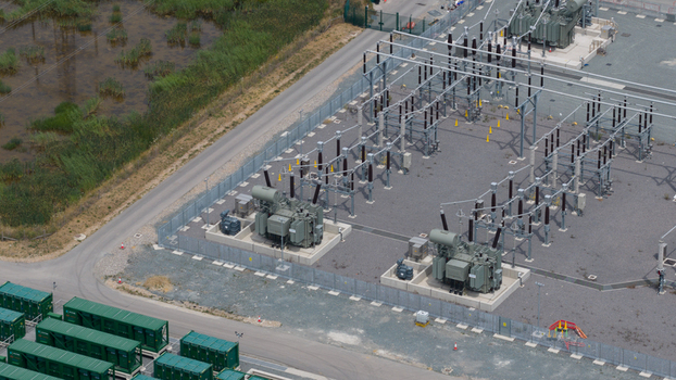 Aerial view of Thurrock Flexible Generation Substation with electrical transformers power infrastructure and green storage containers on a gravel site in Tilbury England United Kingdom.