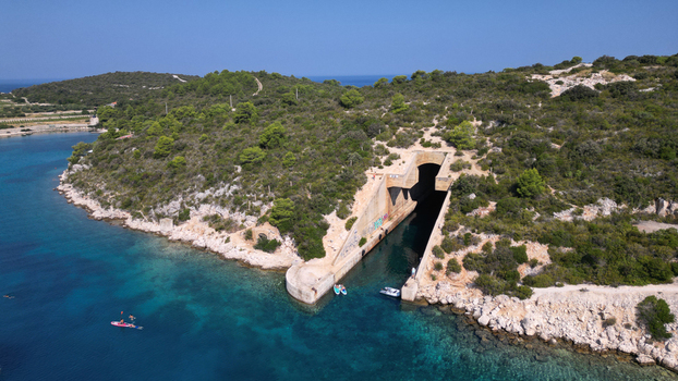 Aerial view of the Yugoslav army underground boat shelter Potkop Parja carved into the rocky coastline with turquoise water and lush green hills Rogacic Splitsko dalmatinska Croatia. Aerial view of the Yugoslav army underground boat shelter Potkop Parja carved into the rocky coastline with turquoise water and lush green hills Rogacic Splitsko dalmatinska Croatia.