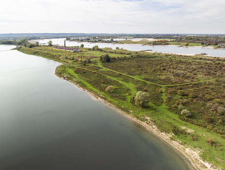Aerial view of the nature reserve Millingerwaard with winding paths lush green meadows and a historic brick building between river Waal and a side channel in Kekerdom Gelderland Netherlands.