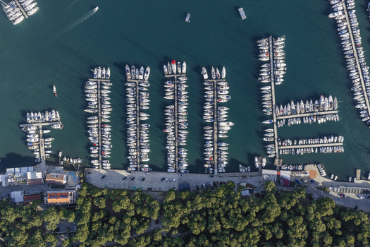 Aerial view of numerous sailboats and yachts docked in the marina with turquoise water wooden piers and surrounding lush green pine forest Pjescana Uvala Pula Istarska Zupanija Croatia.