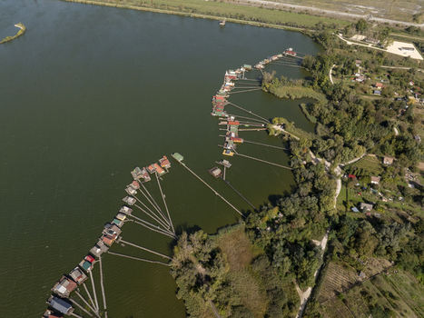Aerial view of Bokodi Floating Village with its iconic wooden houses on stilts over the water connected by long wooden walkways surrounded by lush greenery in Oroszlany Hungary. Aerial view of Bokodi Floating Village with its iconic wooden houses on stilts over the water connected by long wooden walkways surrounded by lush greenery in Oroszlany Hungary.