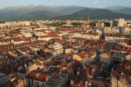 Aerial view of the historic city of Grenoble with characteristic red tiled rooftops urban architecture and the surrounding Alpine mountain range in Grenoble Auvergne Rhone Alpes France.
