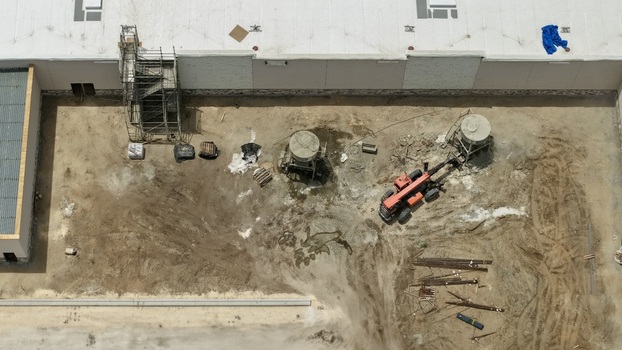 Aerial view of a construction site featuring a red telehandler scaffolding and industrial equipment next to a large white building in World Golf Village Florida United States.