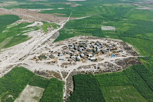 Aerial view of a small rural village surrounded by vast green agricultural fields and dirt paths in Joypurhat Rajshahi Division Bangladesh. Aerial view of a small rural village surrounded by vast green agricultural fields and dirt paths in Joypurhat Rajshahi Division Bangladesh.