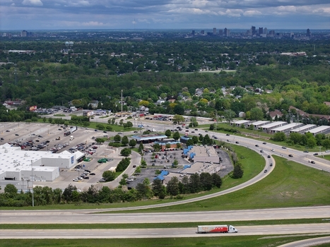 Aerial view of a suburban landscape with commercial buildings parking lots and a highway leading towards a distant city skyline under a cloudy sky Columbus Ohio United States. Aerial view of a suburban landscape with commercial buildings parking lots and a highway leading towards a distant city skyline under a cloudy sky Columbus Ohio United States.