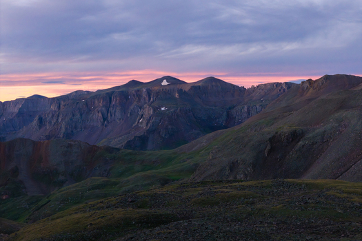 Aerial view of Mount Sneffels in the San Juan Mountain Range at sunset featuring rocky peaks green slopes and dramatic clouds in Ouray Colorado United States. Aerial view of Mount Sneffels in the San Juan Mountain Range at sunset featuring rocky peaks green slopes and dramatic clouds in Ouray Colorado United States.