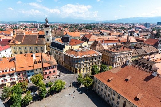 View of the historic Great Square in Sibiu with its characteristic orange tiled rooftops the Council Tower and surrounding medieval architecture under a bright blue sky in Sibiu Sibiu Romania. View of the historic Great Square in Sibiu with its characteristic orange tiled rooftops the Council Tower and surrounding medieval architecture under a bright blue sky in Sibiu Sibiu Romania.