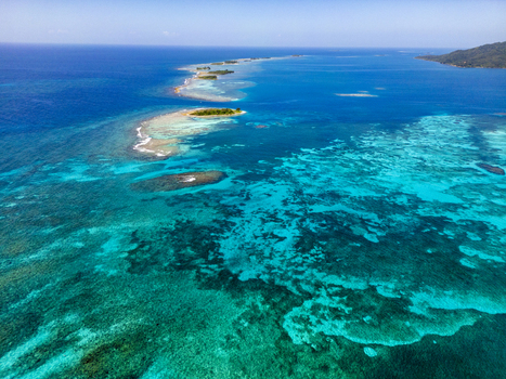 Aerial view of the turquoise waters and coral reefs surrounding the tropical island chain under a clear blue sky in Guanaja Bay Islands Department Honduras. Aerial view of the turquoise waters and coral reefs surrounding the tropical island chain under a clear blue sky in Guanaja Bay Islands Department Honduras.
