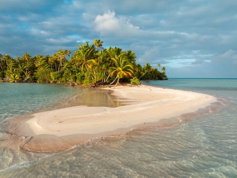 Aerial view of a pristine white sandbar surrounded by turquoise waters and lush palm trees under a cloudy sky in Moorea Maiao Windward Islands French Polynesia. Aerial view of a pristine white sandbar surrounded by turquoise waters and lush palm trees under a cloudy sky in Moorea Maiao Windward Islands French Polynesia.