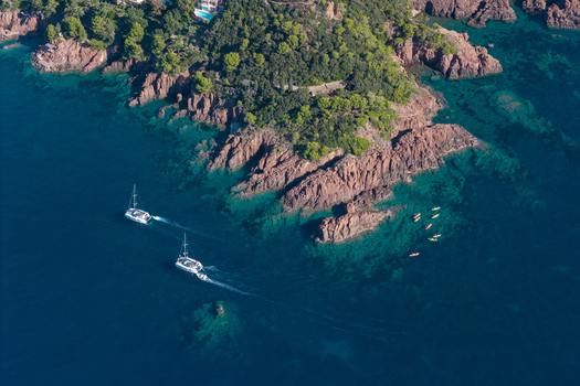 Aerial view of Le Trayas with its rugged red rock coastline turquoise waters sailing catamarans and colorful kayaks near the shore in Saint Raphael Provence Alpes Cote d Azur France. Aerial view of Le Trayas with its rugged red rock coastline turquoise waters sailing catamarans and colorful kayaks near the shore in Saint Raphael Provence Alpes Cote d Azur France.