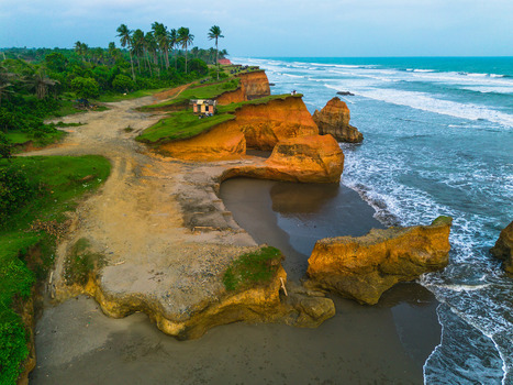 Aerial view of orange coastal cliffs with lush palm trees and turquoise ocean waves crashing against the shore Bali Bali Indonesia. Aerial view of orange coastal cliffs with lush palm trees and turquoise ocean waves crashing against the shore Bali Bali Indonesia.