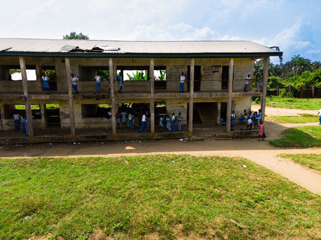 Aerial view of a two story school building with students in blue uniforms standing on balconies overlooking a grassy field in Ahoada I Rivers Nigeria. Aerial view of a two story school building with students in blue uniforms standing on balconies overlooking a grassy field in Ahoada I Rivers Nigeria.