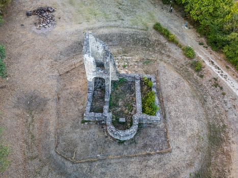 Aerial view of the medieval Csabdi church ruins with surviving stone walls and an arched apse in an open rural clearing surrounded by trees in Csabdi Hungary.
