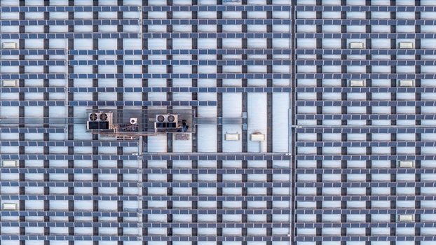 Aerial view of a datacenter roof covered in rows of solar panels with integrated HVAC cooling units in Settecamini Lazio Italy.