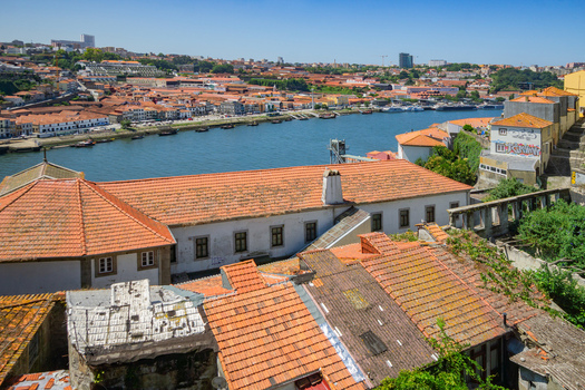 Aerial view of terracotta rooftops cascading towards the shimmering Douro River with Ribeira s historic buildings lining the waterfront Porto Porto District Portugal. Aerial view of terracotta rooftops cascading towards the shimmering Douro River with Ribeira s historic buildings lining the waterfront Porto Porto District Portugal.