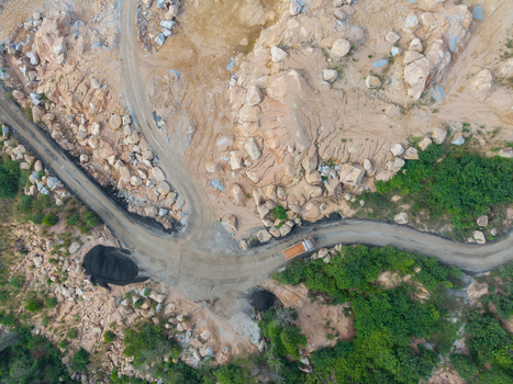Aerial view of a mining site with a dump truck driving along a dirt road surrounded by rocky terrain and lush green vegetation in Bukit Tambun Penang Malaysia. Aerial view of a mining site with a dump truck driving along a dirt road surrounded by rocky terrain and lush green vegetation in Bukit Tambun Penang Malaysia.