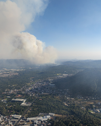Aerial view of a large wildfire producing thick smoke over the landscape near the town of Uruapan Michoacan Mexico.