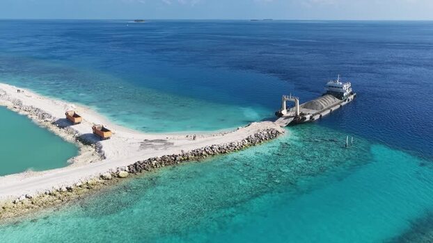 Aerial view of a cargo ship unloading sand on a reef Maldives. Aerial view of a cargo ship unloading sand on a reef Maldives.