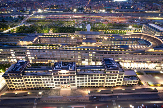 Aerial view of the historic Lingotto building featuring its iconic rooftop test track illuminated at night in Turin Piedmont Italy. Aerial view of the historic Lingotto building featuring its iconic rooftop test track illuminated at night in Turin Piedmont Italy.