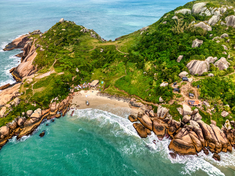 Aerial view of Praia do Gravata with sandy beach nestled between granite boulders and lush hills with turquoise waves crashing against the coast Florianopolis Santa Catarina Brazil. Aerial view of Praia do Gravata with sandy beach nestled between granite boulders and lush hills with turquoise waves crashing against the coast Florianopolis Santa Catarina Brazil.