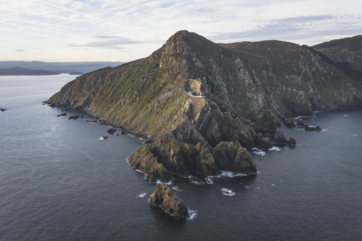 Aerial view of a lighthouse perched on the rugged cliffs of the coastline in Galicia Spain.