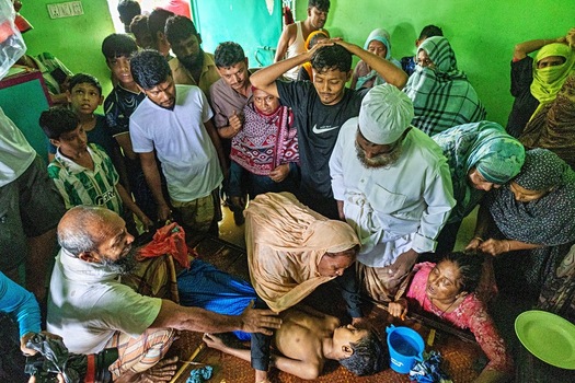 Banshkhali Upazila Bangladesh 10 July 2026 View of a group of concerned people gathered around a young boy lying on a mat indoors. Banshkhali Upazila Bangladesh 10 July 2026 View of a group of concerned people gathered around a young boy lying on a mat indoors.