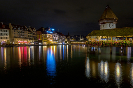 View of the illuminated Chapel Bridge and historic waterfront buildings reflecting in the Reuss river at night Lucerne Lucerne Switzerland. View of the illuminated Chapel Bridge and historic waterfront buildings reflecting in the Reuss river at night Lucerne Lucerne Switzerland.