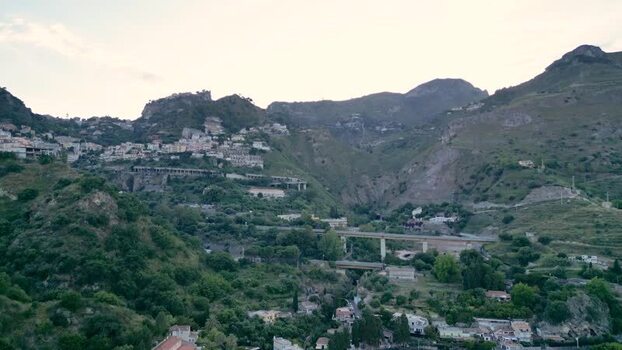 Aerial view of hillside buildings and mountains in Taormina Italy.