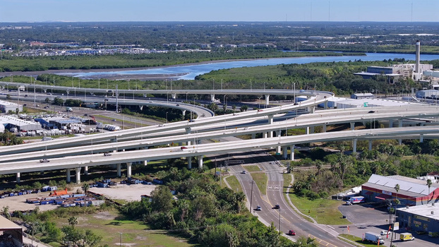 Aerial view of the complex highway interchange with multi level concrete overpasses flowing traffic industrial buildings and lush vegetation in Tampa Florida United States. Aerial view of the complex highway interchange with multi level concrete overpasses flowing traffic industrial buildings and lush vegetation in Tampa Florida United States.