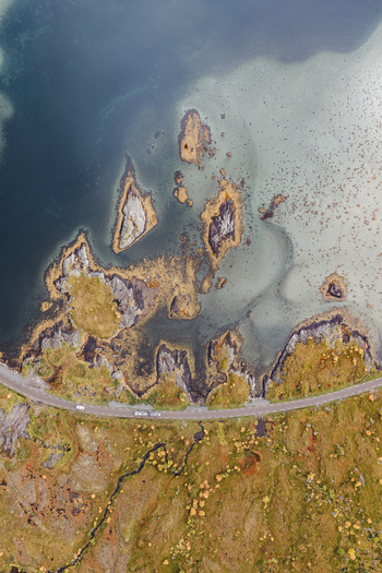 Aerial view of the rugged coastline of Lofoten with a winding road rocky islands and shallow coastal waters in Leknes Nordland Norway. Aerial view of the rugged coastline of Lofoten with a winding road rocky islands and shallow coastal waters in Leknes Nordland Norway.