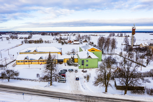 Aerial view of a colorful school building complex surrounded by a snow covered rural landscape with a parking lot and a communication tower in Latvia. Aerial view of a colorful school building complex surrounded by a snow covered rural landscape with a parking lot and a communication tower in Latvia.
