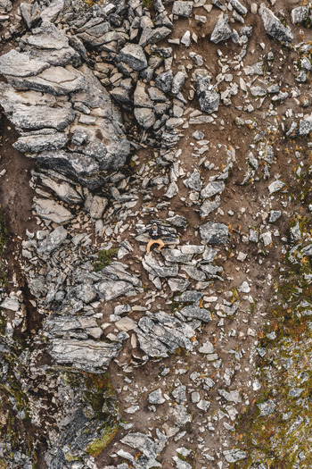 Aerial view of a person sitting on rocky terrain in the rugged landscape of Senja Troms Norway.