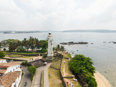 Aerial view of the historic Galle Lighthouse and stone fortifications surrounded by palm trees and the Indian Ocean in Galle Southern Province Sri Lanka. Aerial view of the historic Galle Lighthouse and stone fortifications surrounded by palm trees and the Indian Ocean in Galle Southern Province Sri Lanka.