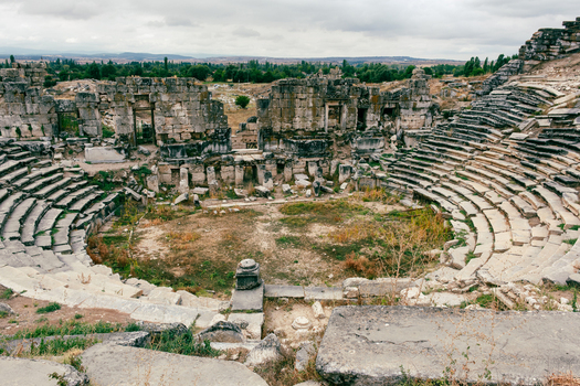 View of the ancient Roman theater of Aizonai with weathered stone seating and historic ruins under a cloudy sky in Cavdarhisar Kutahya Turkiye. View of the ancient Roman theater of Aizonai with weathered stone seating and historic ruins under a cloudy sky in Cavdarhisar Kutahya Turkiye.