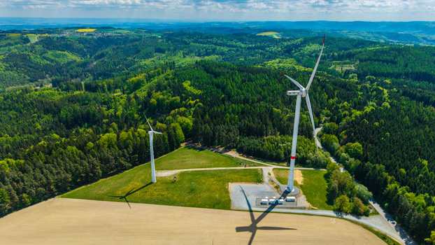 Aerial view of Zipotin wind turbines standing on a grassy hill surrounded by lush green forests and rolling hills under a bright sky Gruna Pardubicky kraj Czechia. Aerial view of Zipotin wind turbines standing on a grassy hill surrounded by lush green forests and rolling hills under a bright sky Gruna Pardubicky kraj Czechia.