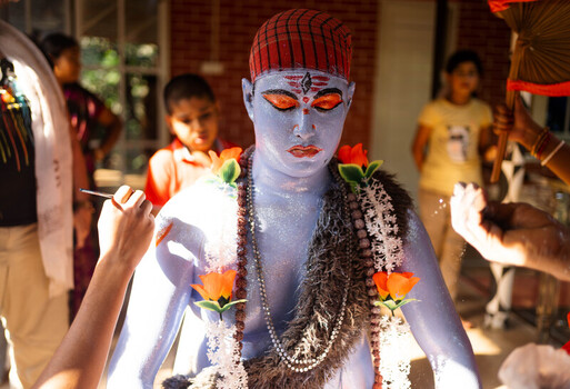 Munshiganj Bangladesh 13 April 2025 View of a performer meticulously painted in vibrant blue and adorned with bright orange garlands being prepared for a cultural celebration amidst soft light. Munshiganj Bangladesh 13 April 2025 View of a performer meticulously painted in vibrant blue and adorned with bright orange garlands being prepared for a cultural celebration amidst soft light.