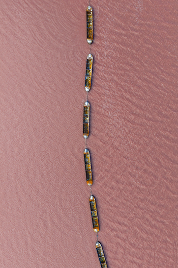 Aerial view of boats sailing on the pink waters of Las Salinas a striking contrast of colors and textures under the sun San Pedro del Pinatar Region of Murcia Spain. Aerial view of boats sailing on the pink waters of Las Salinas a striking contrast of colors and textures under the sun San Pedro del Pinatar Region of Murcia Spain.
