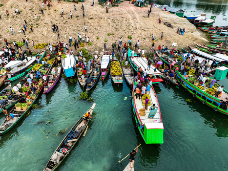 Rangamati Hill District Bangladesh 18 May 2024 Aerial view of Kaptai Lake with numerous wooden boats loaded with fresh produce and people gathering on the riverbank in a bustling local market.
