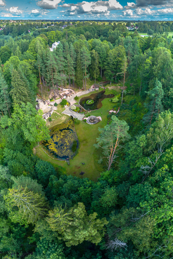 Aerial view of a lush green park with small ponds stone bridges and walking paths surrounded by dense pine forests in Latvia. Aerial view of a lush green park with small ponds stone bridges and walking paths surrounded by dense pine forests in Latvia.