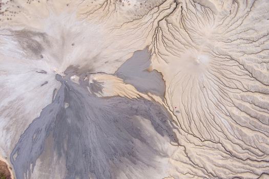 Aerial view of the Mud Volcanoes of Paclele Mari showcasing intricate radial patterns of dried grey and beige mud flows in Paclele Buzau County Romania.