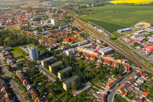 Aerial view of residential buildings a railway line and lush green fields under a bright sky in Kyjov South Moravian Region Czechia.