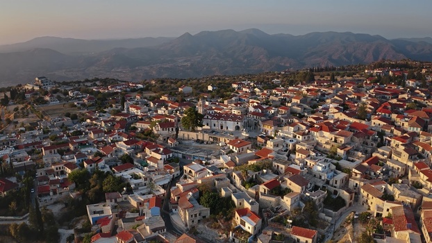 Aerial view of the village of Omodos with its traditional stone houses red tiled roofs and central church square nestled against the Troodos mountains in Omodos Cyprus. Aerial view of the village of Omodos with its traditional stone houses red tiled roofs and central church square nestled against the Troodos mountains in Omodos Cyprus.