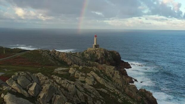 Aerial view of Faro de Punta Nariga on rocky cliffs in Spain.