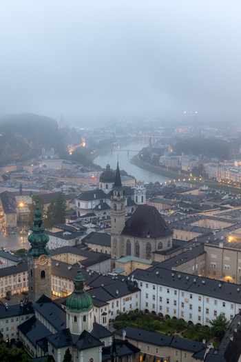 Aerial view of the historic old town of Salzburg with its iconic church spires winding river and traditional rooftops under a misty sky in Salzburg Salzburg Austria. Aerial view of the historic old town of Salzburg with its iconic church spires winding river and traditional rooftops under a misty sky in Salzburg Salzburg Austria.